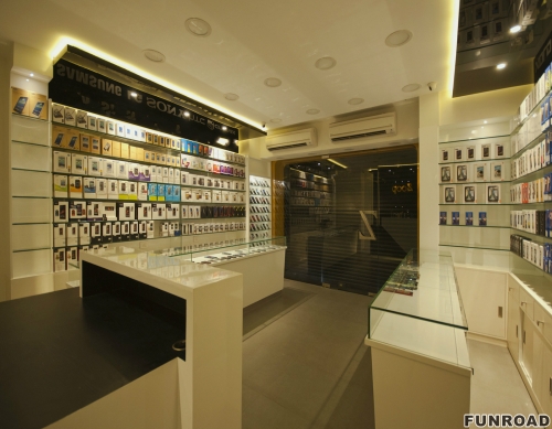 Small warm decorated mobile phone shop interior design with glass accessories display shelves and counter