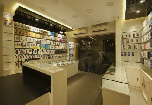 Small warm decorated mobile phone shop interior design with glass accessories display shelves and counter