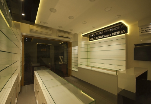 Small warm decorated mobile phone shop interior design with glass accessories display shelves and counter
